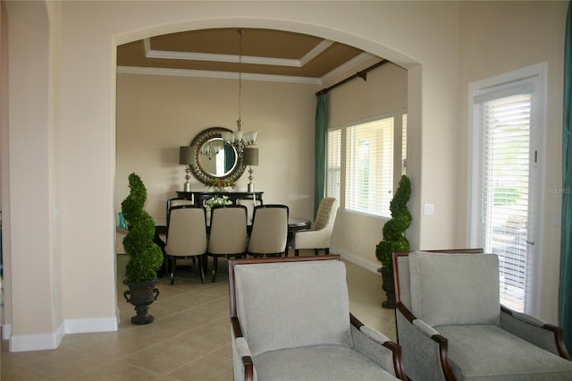 dining area featuring a raised ceiling, arched walkways, a chandelier, baseboards, and ornamental molding