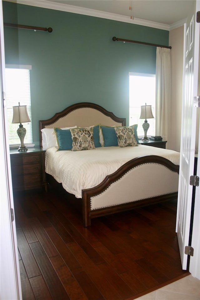 bedroom featuring multiple windows, ornamental molding, and dark wood-type flooring