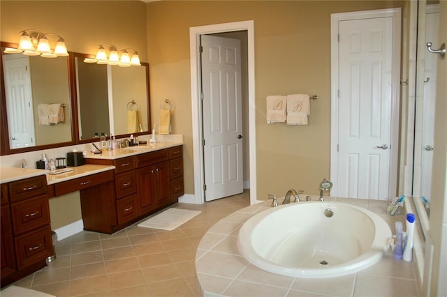 bathroom with vanity, tile patterned floors, baseboards, and a bath