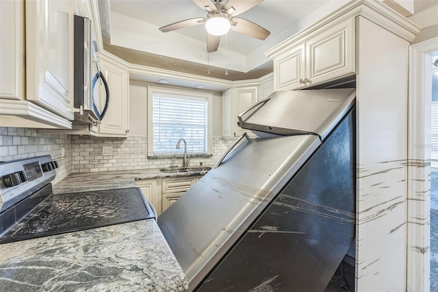 15406 2nd St E, Madeira Beach, FL 33708 - kitchen featuring ceiling fan, appliances with stainless steel finishes, light stone countertops, a sink, and decorative backsplash