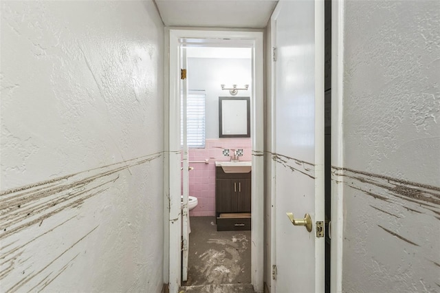 15406 2nd St E, Madeira Beach, FL 33708 - bathroom with a textured wall, vanity, toilet, a wainscoted wall, and tile walls