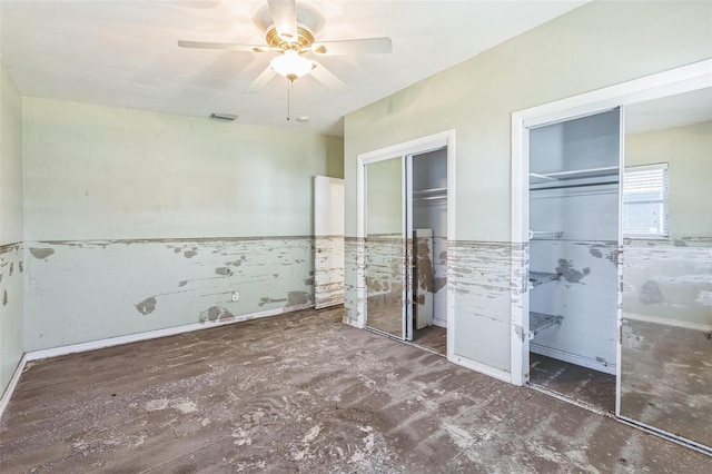 15406 2nd St E, Madeira Beach, FL 33708 - unfurnished bedroom featuring visible vents, a ceiling fan, wainscoting, and two closets