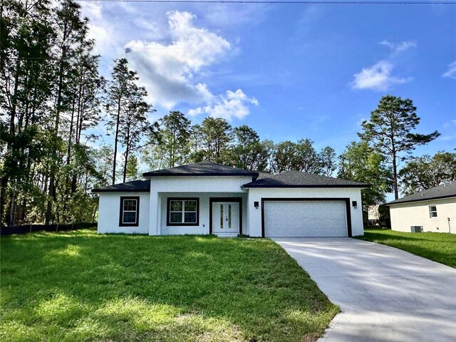 prairie-style home featuring a front lawn, an attached garage, concrete driveway, and stucco siding