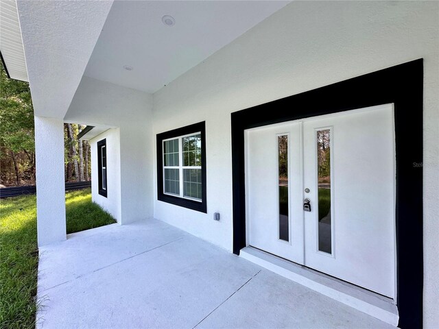 doorway to property with french doors, a patio, and stucco siding