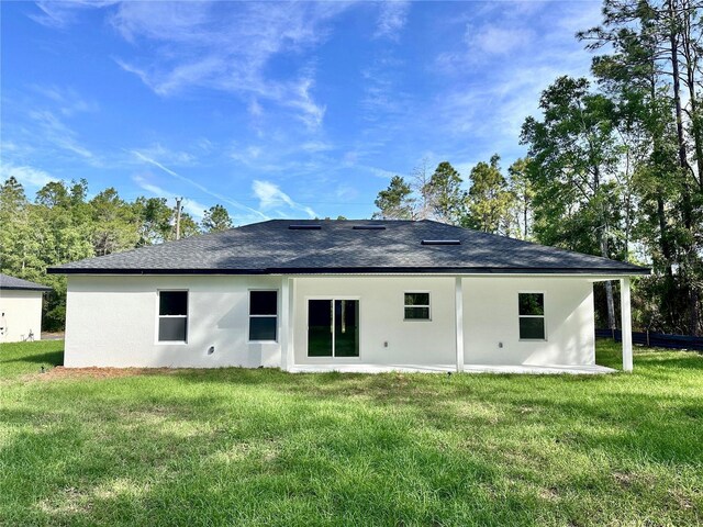 rear view of house with a lawn, roof with shingles, and stucco siding