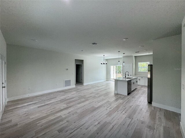 kitchen featuring freestanding refrigerator, open floor plan, a sink, and light wood-type flooring