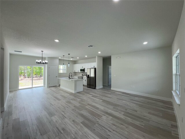 kitchen with an inviting chandelier, a sink, stainless steel appliances, open floor plan, and recessed lighting