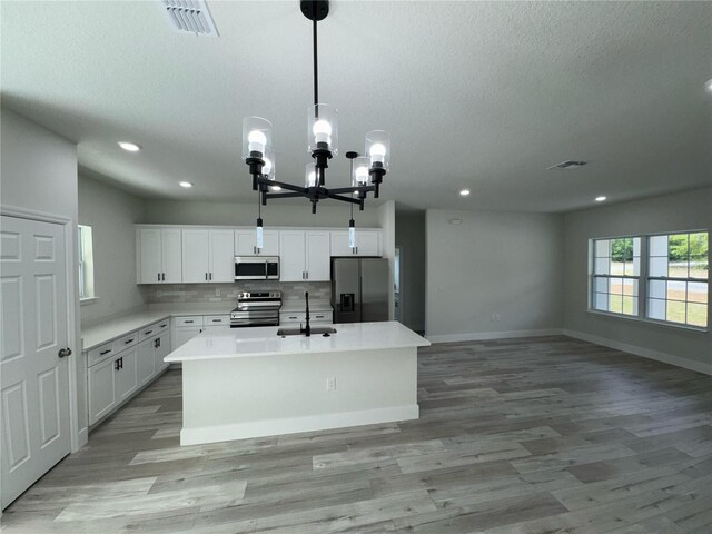 kitchen featuring an inviting chandelier, a sink, appliances with stainless steel finishes, and light wood-type flooring