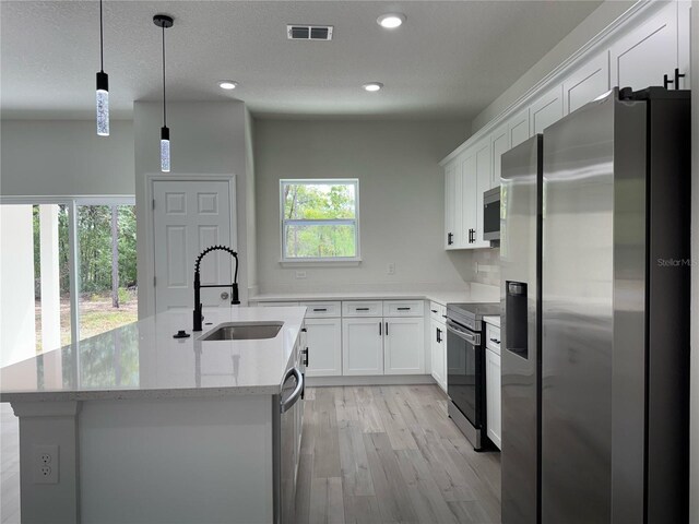 kitchen featuring visible vents, light wood-type flooring, a sink, white cabinets, and stainless steel appliances
