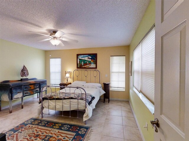 bedroom with baseboards, a textured ceiling, ceiling fan, and light tile patterned floors