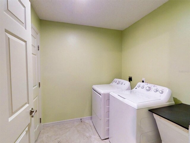 clothes washing area with separate washer and dryer, laundry area, baseboards, and marble finish floor