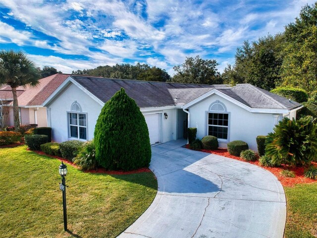 ranch-style home with stucco siding, concrete driveway, a front yard, and a garage
