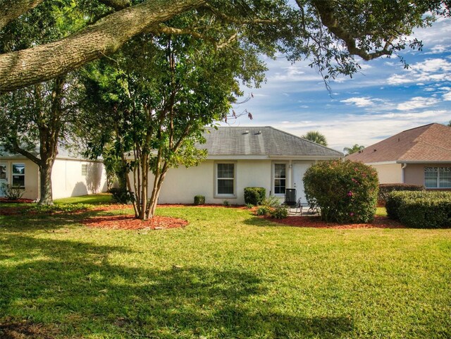 back of property featuring a lawn and stucco siding