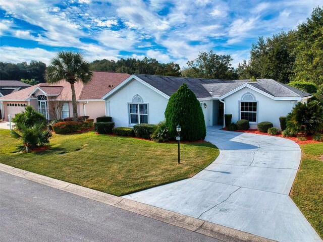 single story home with curved driveway, stucco siding, and a front yard