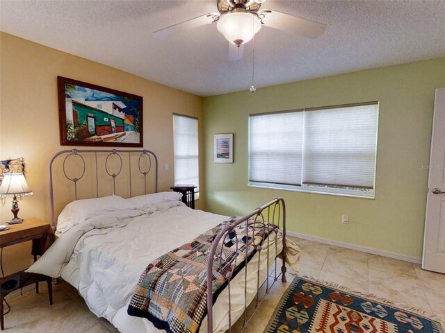bedroom with a ceiling fan, a textured ceiling, and tile patterned flooring