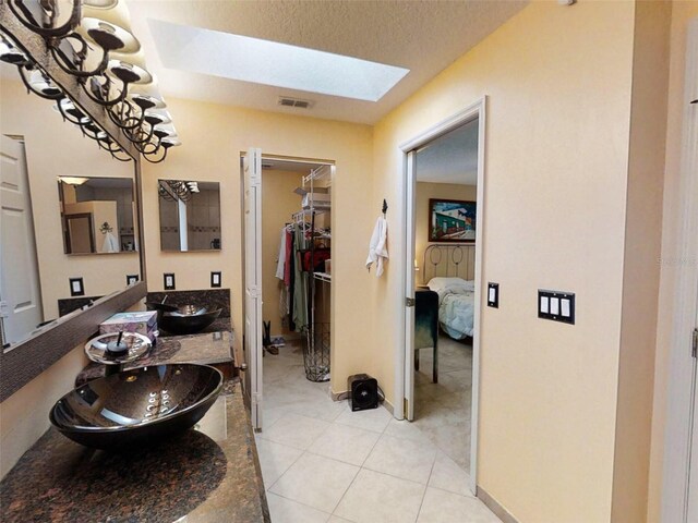 bathroom featuring a sink, double vanity, tile patterned floors, a skylight, and visible vents