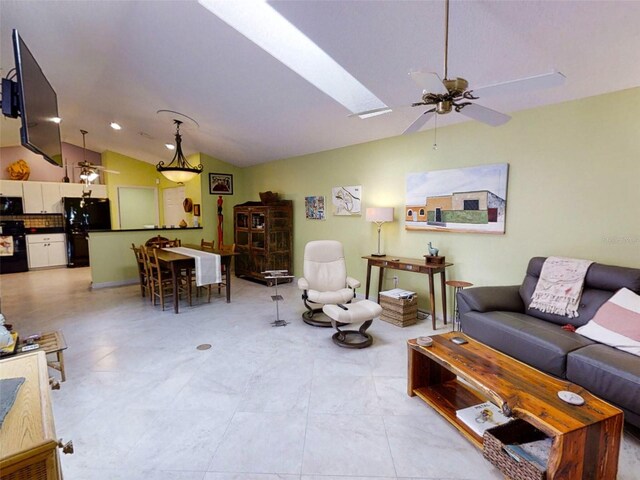 living area with lofted ceiling with skylight and ceiling fan