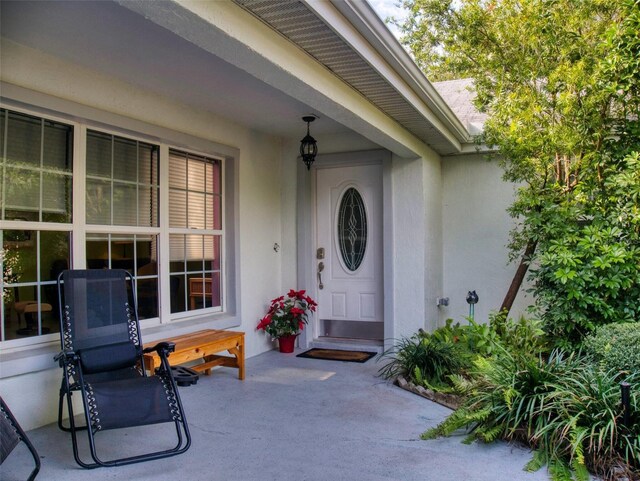 property entrance featuring covered porch and stucco siding