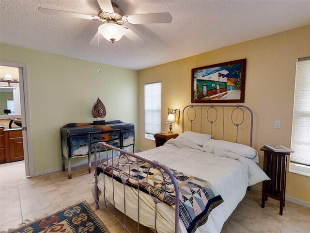 bedroom featuring a ceiling fan, a textured ceiling, light tile patterned floors, and multiple windows