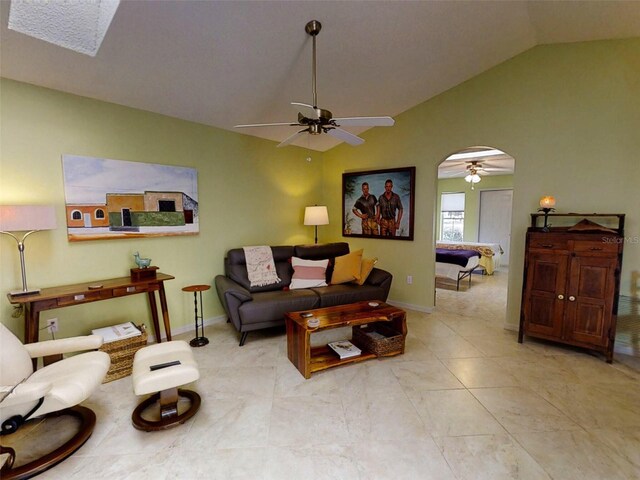 living room with arched walkways, ceiling fan, vaulted ceiling, and baseboards