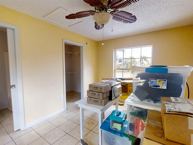 interior space featuring a textured ceiling, a spacious closet, light tile patterned floors, and a closet
