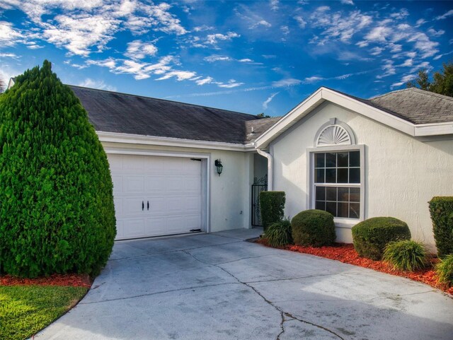 single story home featuring an attached garage, stucco siding, and concrete driveway
