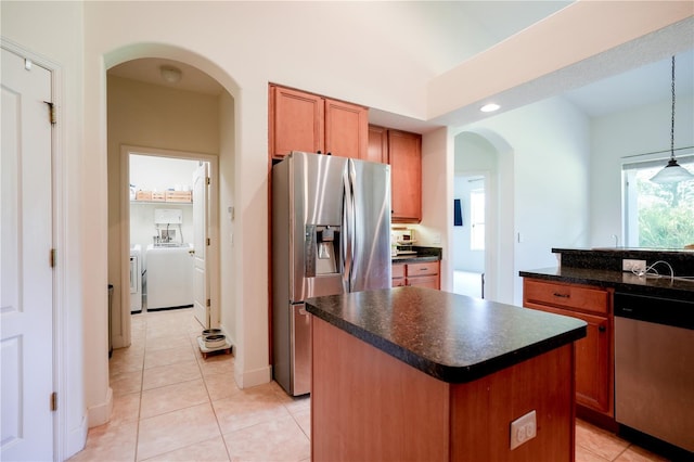 23533 Valderama Ln, Sorrento, FL 32776 - kitchen with dark countertops, stainless steel appliances, light tile patterned floors, a kitchen island, and washer and clothes dryer