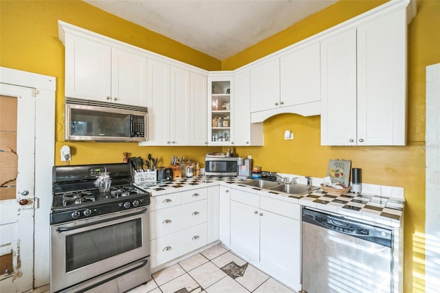 419 Palm Ave, Eustis, FL 32726 - kitchen with a sink, stainless steel appliances, tile countertops, white cabinetry, and glass insert cabinets