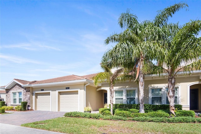 view of front of home with an attached garage, stucco siding, driveway, and a tile roof