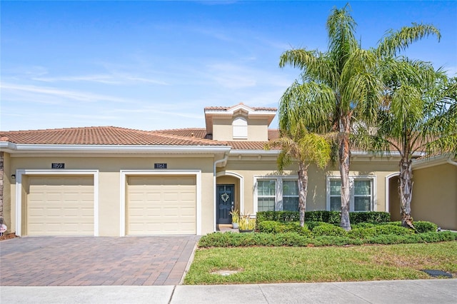 view of front of home featuring an attached garage, decorative driveway, stucco siding, and a tile roof