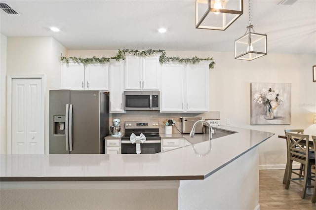 kitchen with white cabinets, appliances with stainless steel finishes, decorative backsplash, wood finished floors, and visible vents