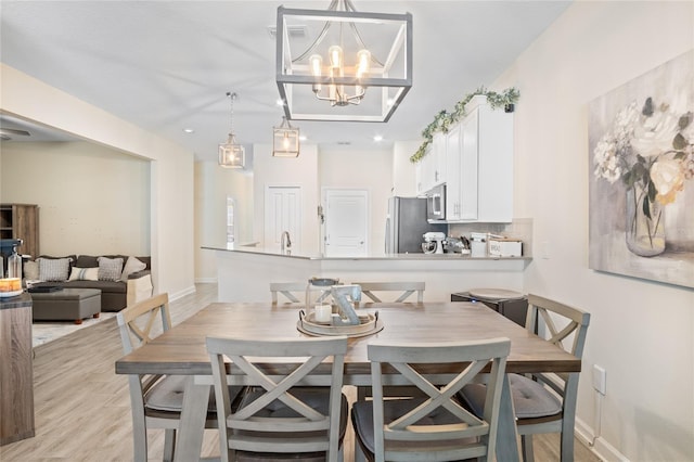 dining space featuring recessed lighting, baseboards, a notable chandelier, and light wood-style floors