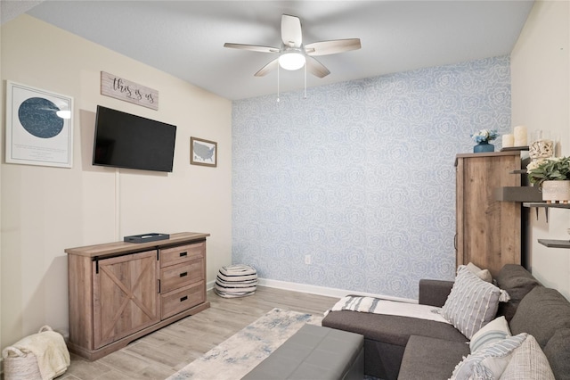 living room featuring baseboards, wallpapered walls, ceiling fan, and light wood-style floors