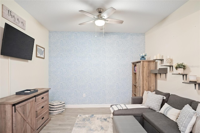 sitting room with baseboards, ceiling fan, light wood finished floors, and wallpapered walls