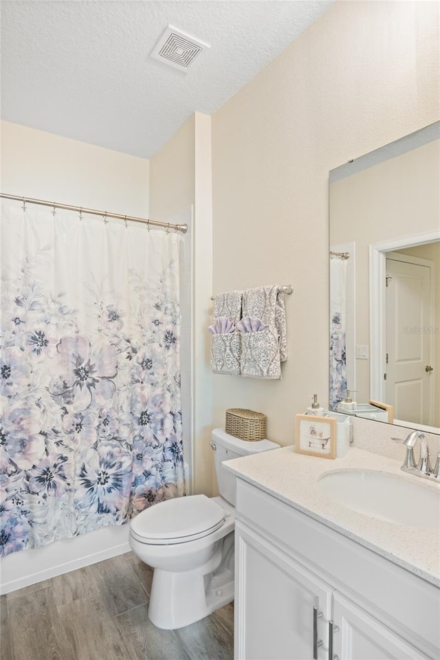 bathroom with visible vents, wood finished floors, toilet, and vanity