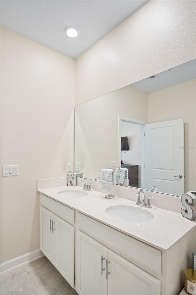 bathroom with double vanity, baseboards, visible vents, and a sink