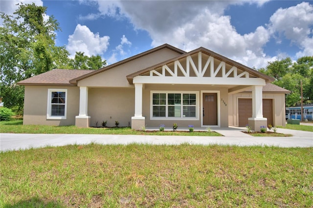 view of front of property with an attached garage, a front yard, stucco siding, and driveway