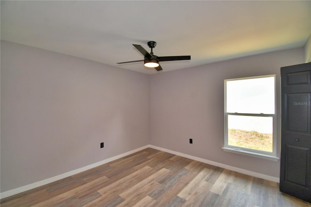 spare room featuring baseboards, wood finished floors, and ceiling fan
