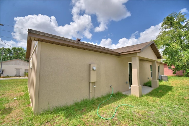 rear view of property with stucco siding, a lawn, and central AC unit