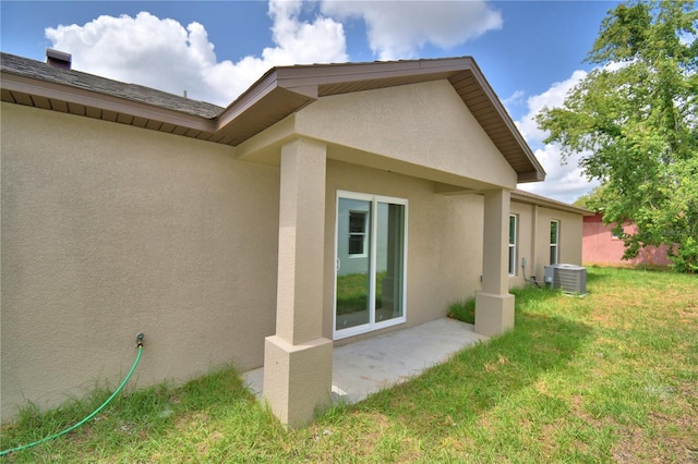 view of property exterior featuring stucco siding, central AC unit, and a lawn