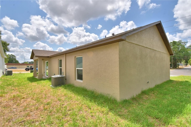 view of home's exterior featuring stucco siding, a lawn, and central AC unit