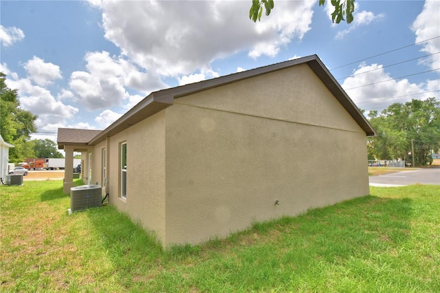 view of home's exterior featuring stucco siding, central air condition unit, and a yard