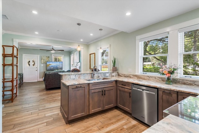 kitchen with a sink, dishwasher, a peninsula, light stone counters, and crown molding