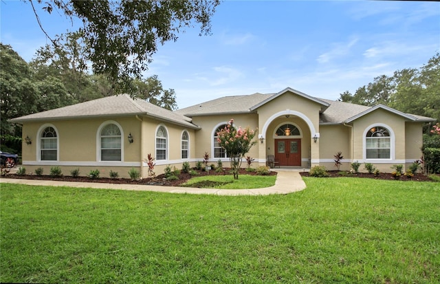 view of front of property featuring roof with shingles, stucco siding, french doors, and a front yard
