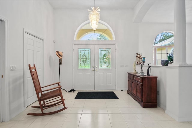 foyer entrance featuring an inviting chandelier, arched walkways, light tile patterned floors, and baseboards