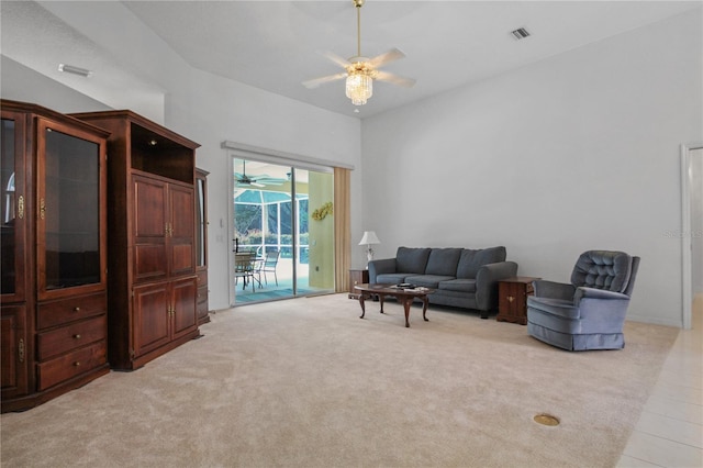 living area with a ceiling fan, light colored carpet, visible vents, and a towering ceiling