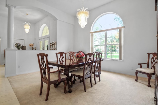 dining space featuring decorative columns, light carpet, baseboards, a high ceiling, and arched walkways