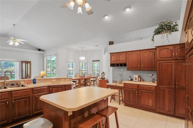 kitchen with a ceiling fan, a sink, lofted ceiling, and light countertops