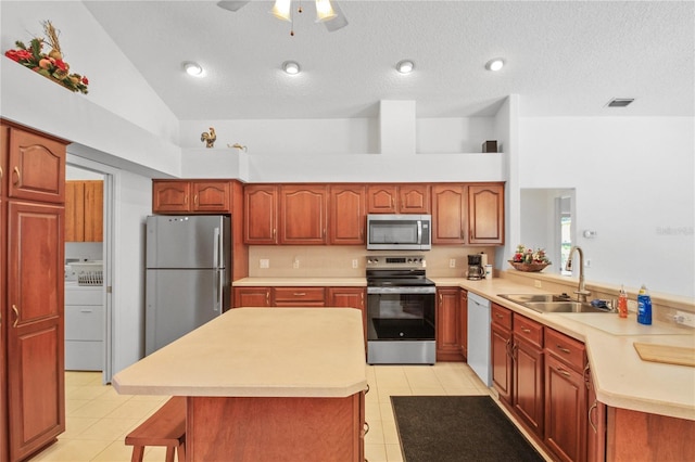 kitchen featuring visible vents, washer / dryer, light countertops, a sink, and appliances with stainless steel finishes