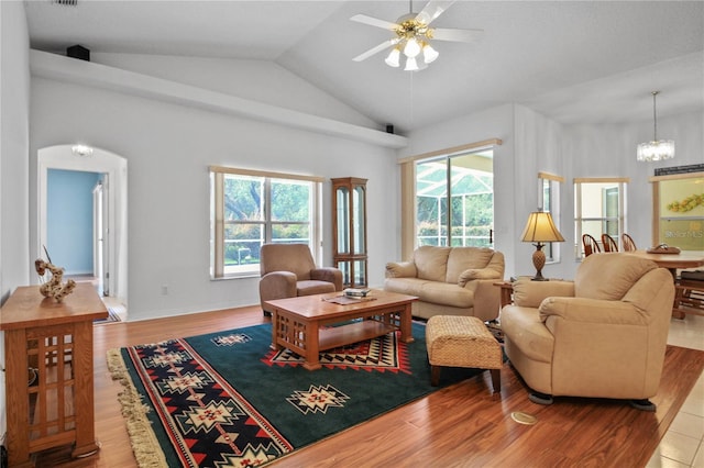 living area with wood finished floors, ceiling fan with notable chandelier, lofted ceiling, and a wealth of natural light